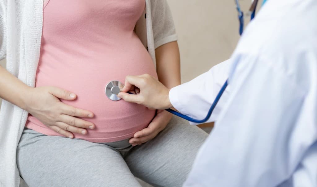 A doctor listening to a pregnant patient's abdomen with a stethoscope